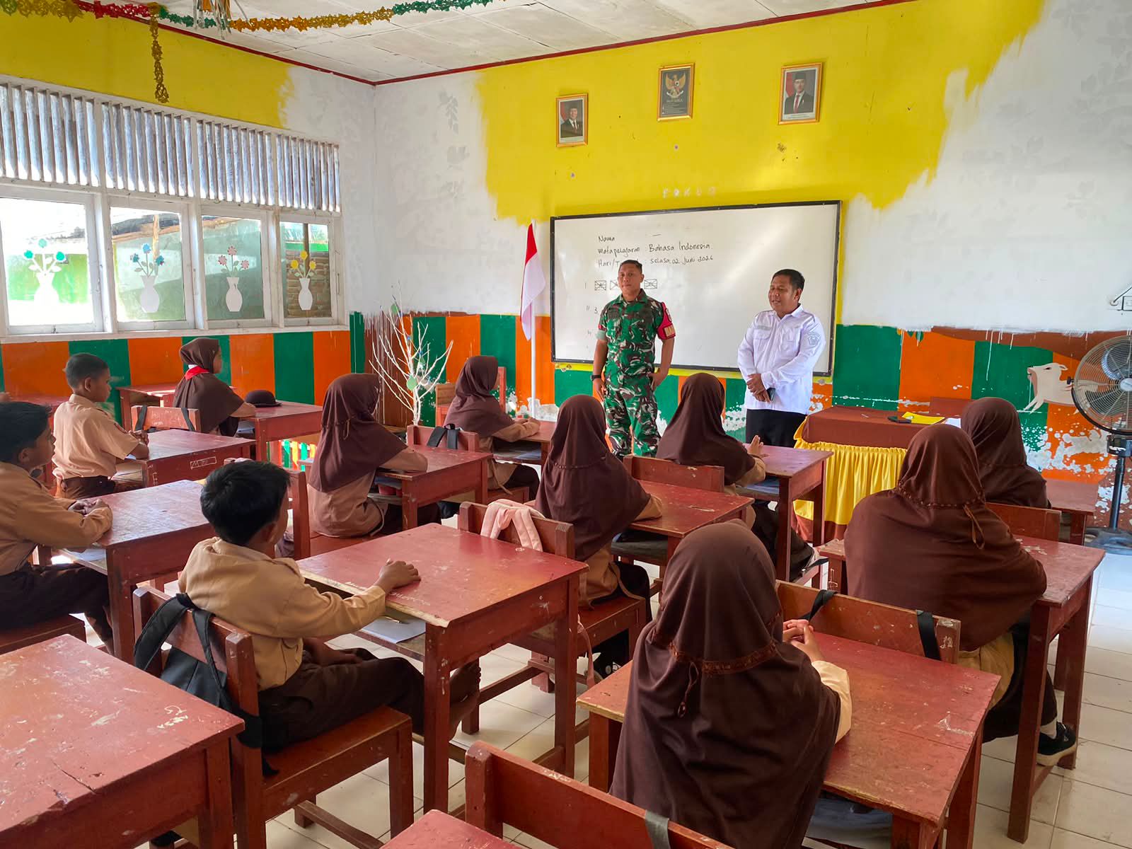 Guru dan tentara berbicara di depan kelas saat siswa duduk mendengarkan